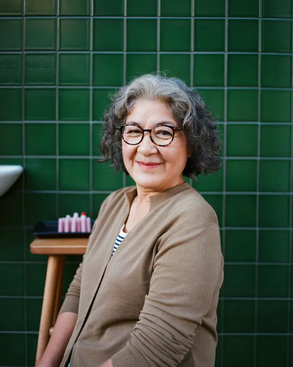 Joy sitting by the basins with a tray of perm rods.