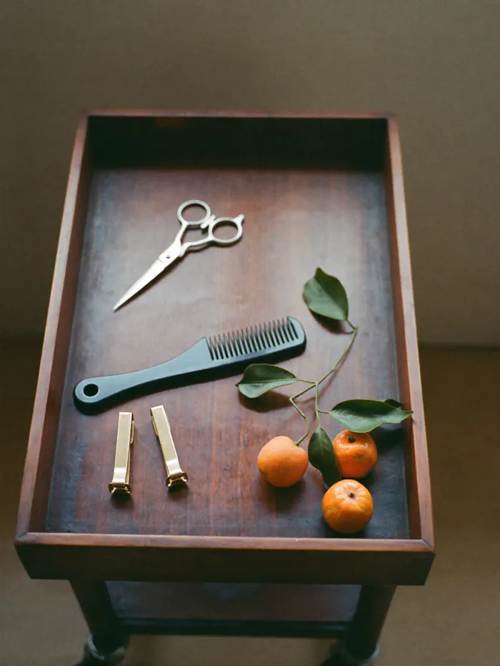 Scissors, a tail comb, two clips and a loquat branch on the wooden trolley.